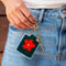 model holding green needlepoint keychain kit with baby blue trim, orange flower print and gold hardware
