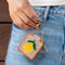 model holding tan needlepoint keychain kit with orange trim and lemon print and gold hardware