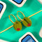 up close of olive dangle earrings on gold hoops