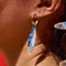 model wearing blue sardine dangle earrings on gold hoops