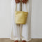 model holding pale yellow leather bucket bag