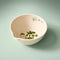 side view of cream colored peel, grate, and herb stem remover bowl with herbs inside