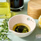 cream colored peel, grate, and herb stem remover bowl with dressing inside