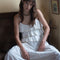 up close of model wearing white tiered lacy tank with matching skirt