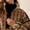 up close of model wearing tan fleece half zip sweatshirt with red floral print and black piping on the arms and zipper