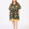 model wearing navy blue babydoll dress with pin-tucked and large white button down the bust, with colorful fruit, baguette and leafy print