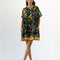 model wearing navy blue babydoll dress with pin-tucked and large white button down the bust, with colorful fruit, baguette and leafy print