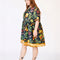 side view of model wearing navy blue babydoll dress with pin-tucked and large white button down the bust, with colorful fruit, baguette and leafy print
