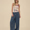 model wearing dark blue denim wide leg pants with drawstring waist and raw hems