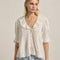 model wearing ivory blouse with embroidered collar and hem, button front and pin-tucked details