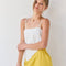 model wearing white handkerchief tank with eyelet floral detail and tie detail