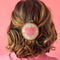 model wearing pink heart cross-stitch french barrette with brown embroidery hoop and iridescent base