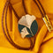 gold ginkgo bolo tie with brown cord and gold tips on a gold ground