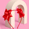 two red bows on the side of a headband standing on a stand