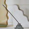 side view of grey stacked glass incense holder with an incense inside on a table