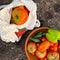 cream open knit market bag with red tomato in the middle and green trim with veggies from a garden