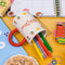 Pens spilling out of the cherry on top mug, laying on its side on a yellow background.