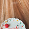 model placing various pieces of jewelry on 'you're the cherry on top' trinket tray with 3D cherry ring holder