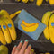 model picking up bananas with small rattan pouch with banana design and zipper top on the display