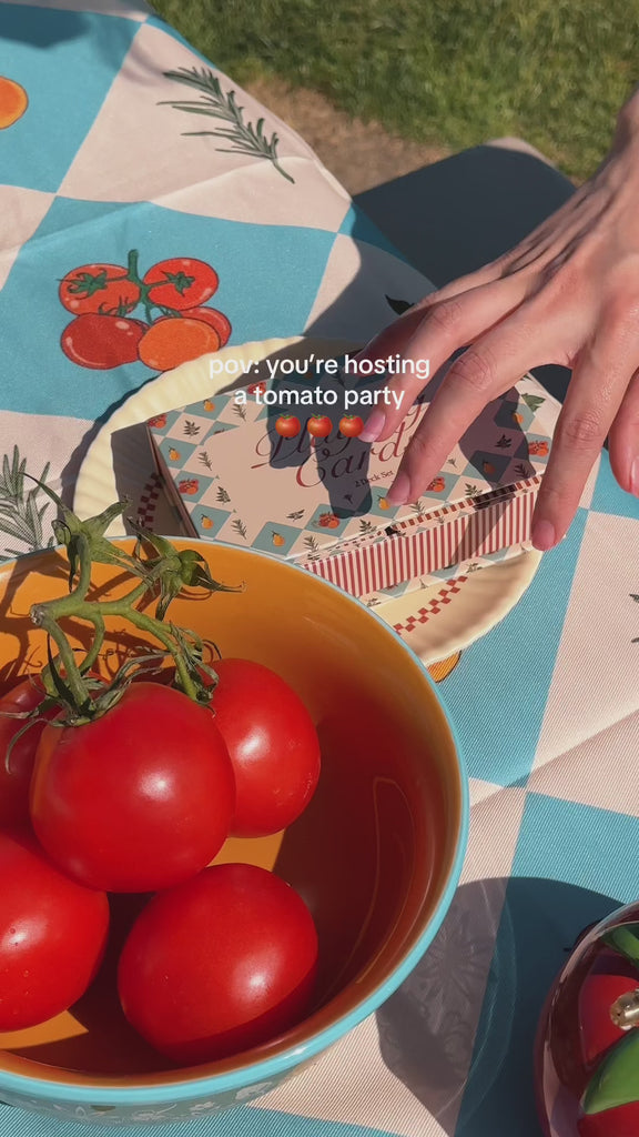 model placing tomato items on fruit picnic blanket