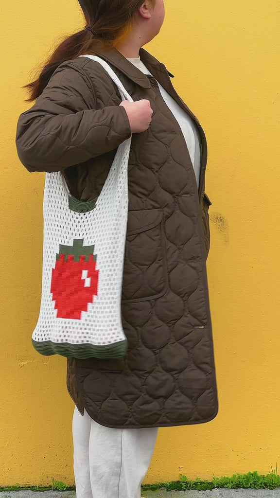 model carrying tote bag that says 'tomatoes are the best' with yellow and red vertical stripes and red handle